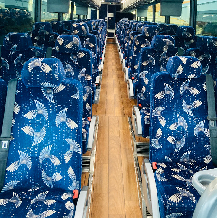 An empty charter bus cabin lined with plush seats