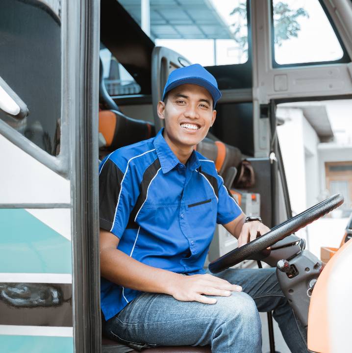 A professional bus driver sits at the wheel of a bus