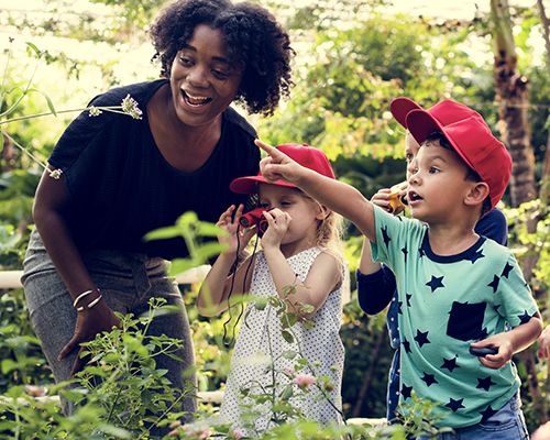 Students and a teacher walk through a garden on a field trip