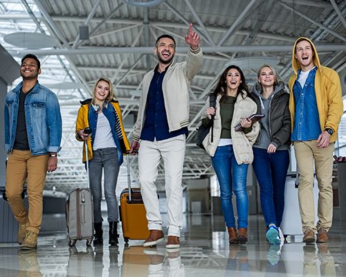 A crowd of airport passengers run through an airport with luggage