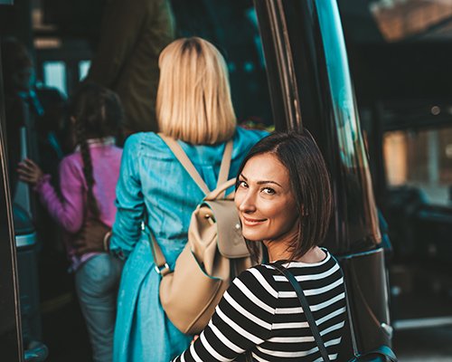 A crowd of passengers board a charter bus shuttle